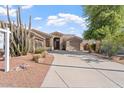 A tan-colored house boasting mature xeriscaping, a three-car garage, and inviting curb appeal in a desert landscape at 4667 E County Down Dr, Chandler, AZ 85249