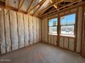 Unfinished bedroom with exposed framing and insulation shows space and window placement at 46868 W Coe St, Maricopa, AZ 85139