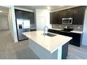 This modern kitchen features dark cabinetry, stainless steel appliances, and a large island with a white countertop at 5645 S 253Rd Ave, Buckeye, AZ 85326