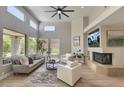 Bright living room with a fireplace, large windows, ceiling fan, and modern decor at 7128 E Bramble Berry Ln, Scottsdale, AZ 85266