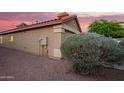 Side view of a home featuring stucco siding, a red tile roof, and desert landscaping against a vibrant twilight backdrop at 8132 E Onza Ave, Mesa, AZ 85212