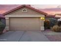 Home exterior showcasing a 2-car garage with a charming desert landscape and a red tile roof under a colorful evening sky at 8132 E Onza Ave, Mesa, AZ 85212