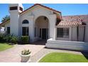 Stunning home exterior with arched entryway and manicured front lawn at 9505 E Jenan Dr, Scottsdale, AZ 85260