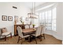 Elegant dining room with a wooden table, seating for six, decorative lighting, and bright windows at 9821 E Windrose Dr, Scottsdale, AZ 85260
