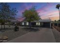 Exterior view of a single-story home with desert landscaping and a spacious carport, as the sun sets at 1003 E Mariposa St, Phoenix, AZ 85014