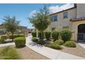 A trimmed green hedge runs beside the walking path along the side of the home at 14870 W Encanto Blvd # 1091, Goodyear, AZ 85395