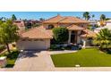 Stunning home features a tile roof, manicured lawn, and an attached three-car garage at 1834 E Willow Tree Ct, Gilbert, AZ 85234