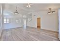 Bright, open-concept living room with arched windows, wood floors, and modern ceiling fan at 21141 N 79Th Ave, Peoria, AZ 85382