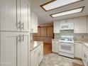 Well-lit kitchen with white appliances, spacious cabinets, and easy access to an adjoining room at 2701 E Allred Ave # 171, Mesa, AZ 85204
