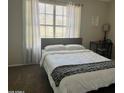 Bright bedroom features a window with sheer curtains, and a full bed with a modern, gray headboard at 4601 N 102Nd Ave # 1052, Phoenix, AZ 85037