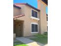 Two-story townhome boasts a stucco exterior, terracotta roof, gated front door, and well-maintained landscaping at 4601 N 102Nd Ave # 1052, Phoenix, AZ 85037