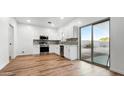 Modern kitchen with stainless steel appliances, white cabinets, and sliding glass doors to the backyard at 6537 W Pioneer St, Phoenix, AZ 85043