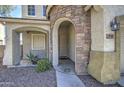 Close up of the home's stone-accented entrance with arched doorway, desert landscaping and welcoming front porch at 8769 W Washington St, Tolleson, AZ 85353