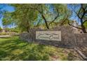 Stone community sign for The Villages at Crismon Creek surrounded by lush green lawns and mature shade trees at 10062 E Isleta Ave, Mesa, AZ 85209