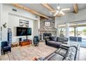 Comfortable living room with a stone fireplace, wood beam accents, and a ceiling fan at 1032 E Dolores Rd, Phoenix, AZ 85086