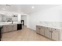 Bright kitchen with marble countertops, stainless steel sink, tile flooring, and ample storage at 10429 W Miami St, Tolleson, AZ 85353