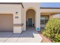 Close-up of a home's entrance featuring an arched doorway, a welcome mat, and desert landscaping at 29481 W Mitchell Ave, Buckeye, AZ 85396