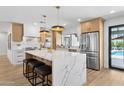 A bright kitchen features white cabinets, quartz countertops, stainless appliances, and an island with stool seating at 4842 E Surrey Ave, Scottsdale, AZ 85254