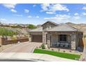 Charming single-story stone home boasts a covered porch with seating, desert landscape, and paver driveway at 520 E Ashurst Dr, Phoenix, AZ 85048