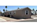 Tan mobile home with desert landscaping, a covered carport, and multiple windows at 625 W Mckellips Rd # 358, Mesa, AZ 85201