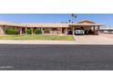 Inviting single-story home with covered parking, lush lawn, and decorative front yard with a welcoming entrance at 10439 W Kingswood Cir, Sun City, AZ 85351