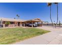 Attractive single-story home boasting a covered carport, well-maintained lawn, and vibrant desert landscaping at 10439 W Kingswood Cir, Sun City, AZ 85351