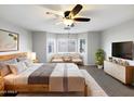 Inviting primary bedroom featuring a bay window, ceiling fan, and warm, neutral decor at 1595 S 227Th Ave, Buckeye, AZ 85326
