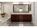Well-lit bathroom with dual sinks, dark wood cabinets, soaking tub, and stylish fixtures at 19889 W Sherman St, Buckeye, AZ 85326