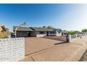 View of house with covered parking area, front yard landscaping and white brick accent wall with horizontal black slat fence at 325 E Harmony Ave, Mesa, AZ 85210