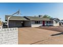 View of house with covered parking area, front yard landscaping, and white brick wall with black metal fence at 325 E Harmony Ave, Mesa, AZ 85210