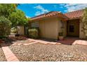 Side view of home with brick paver and rock landscaping leading to tan stucco exterior and trimmed shrubbery at 4225 E Sandia St, Phoenix, AZ 85044