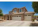 Tan two-story home with a three-car garage, desert landscaping, and neutral-colored trim accents at 7858 W Fetlock Trl, Peoria, AZ 85383