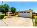 Home featuring a two-car garage and front yard with established desert landscaping at 9714 N 55Th Dr, Glendale, AZ 85302