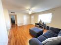 Bright living room with laminate floors, a ceiling fan, and view of the front door at 10726 W Kelso Dr, Sun City, AZ 85351