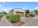 Home featuring a two-car garage, desert landscaping, and a concrete driveway on a sunny day at 14200 W Village Pkwy # 2128, Litchfield Park, AZ 85340
