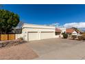 Low angle captures the three-car garage and beige stucco exterior with lovely landscaping against a blue sky at 15602 N 19Th St, Phoenix, AZ 85022