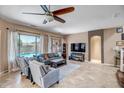 Inviting living room features a ceiling fan, tile floors, and large windows overlooking the backyard pool at 17493 W Arroyo Way, Goodyear, AZ 85338