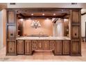 Custom wet bar area featuring dark wood cabinetry, granite countertops, and space for entertaining with a chandelier at 31721 N 138Th Pl, Scottsdale, AZ 85262