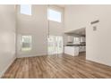 Open-concept living room featuring wood flooring and a large window with views of the backyard at 41251 W Cahill Dr, Maricopa, AZ 85138
