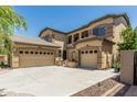 Beige stucco two-story home featuring an arched entryway, desert landscaping, and a 3-car garage with ample parking at 5437 W Red Bird Rd, Phoenix, AZ 85083