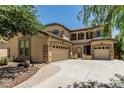 Beige stucco two-story home featuring an arched entryway, desert landscaping, and a 3-car garage with ample parking at 5437 W Red Bird Rd, Phoenix, AZ 85083