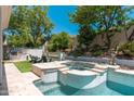 Resort-style backyard with a pool, spa, fire pit, and outdoor kitchen area perfect for entertaining at 7710 E Tardes Dr, Scottsdale, AZ 85255