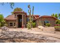 Gorgeous desert home with a stone facade, tile roof, arched entryway, and native cacti in the front yard at 8606 S Dorsey Ln, Tempe, AZ 85284
