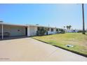 A well-maintained house with a green lawn, covered parking, and mature landscaping at 10307 W Oakmont Dr, Sun City, AZ 85351
