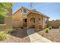 Charming two-story home exterior with a stone archway, landscaping, and walkway at 17802 N 114Th Ln, Surprise, AZ 85378