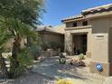 Inviting front entrance with desert landscaping and a covered entryway with a security system sign at 19882 N Crimson Ridge Way, Surprise, AZ 85374