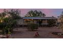 Home exterior featuring desert landscaping with mature plants, covered front porch, and gravel yard at 22216 W Bajada Dr, Wittmann, AZ 85361
