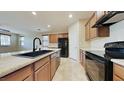Bright kitchen features stone countertops, a black gas range and oven, and stainless fridge at 23853 W Hammond Ln, Buckeye, AZ 85326