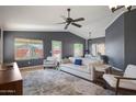 Bright living room with neutral furnishings, a ceiling fan, and a view to the patio at 10786 W Chisholm Dr, Sun City, AZ 85373
