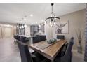 Open concept dining area featuring a wooden table, upholstered chairs, stylish light fixture, and kitchen views at 18835 W San Miguel Ave, Litchfield Park, AZ 85340